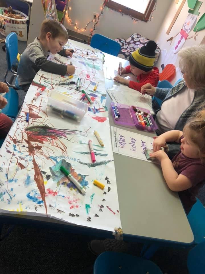 Children and an adult drawing at a table