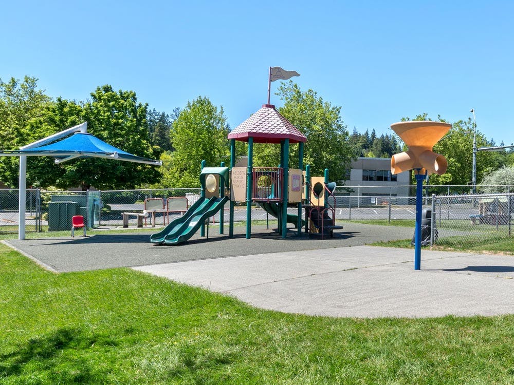 Empty playground with two slides, a play structure, and a large umbrella