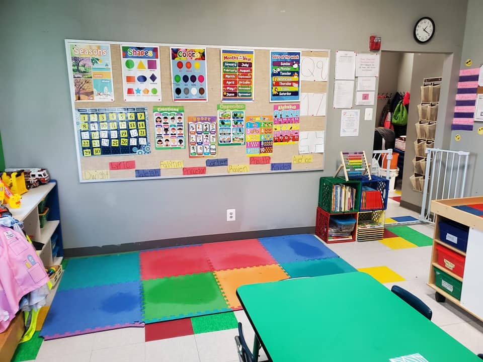 Classroom with colorful floor mats and educational posters on a bulletin board