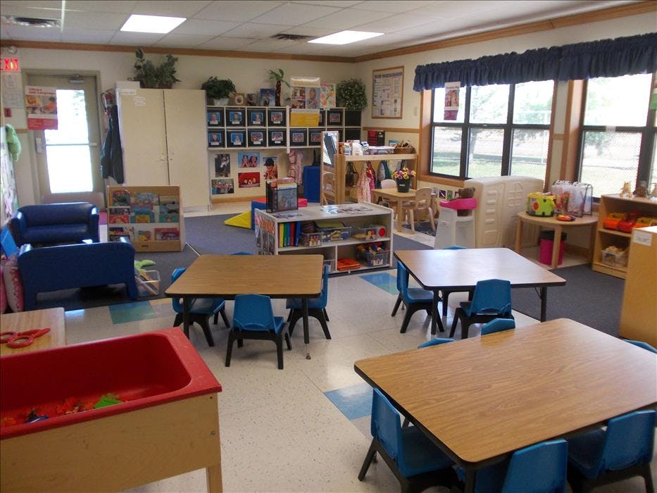 Classroom with small tables and chairs, shelves, and a window