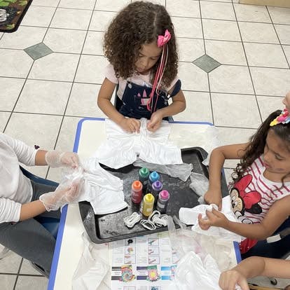 Children and adult preparing fabric for tie-dye