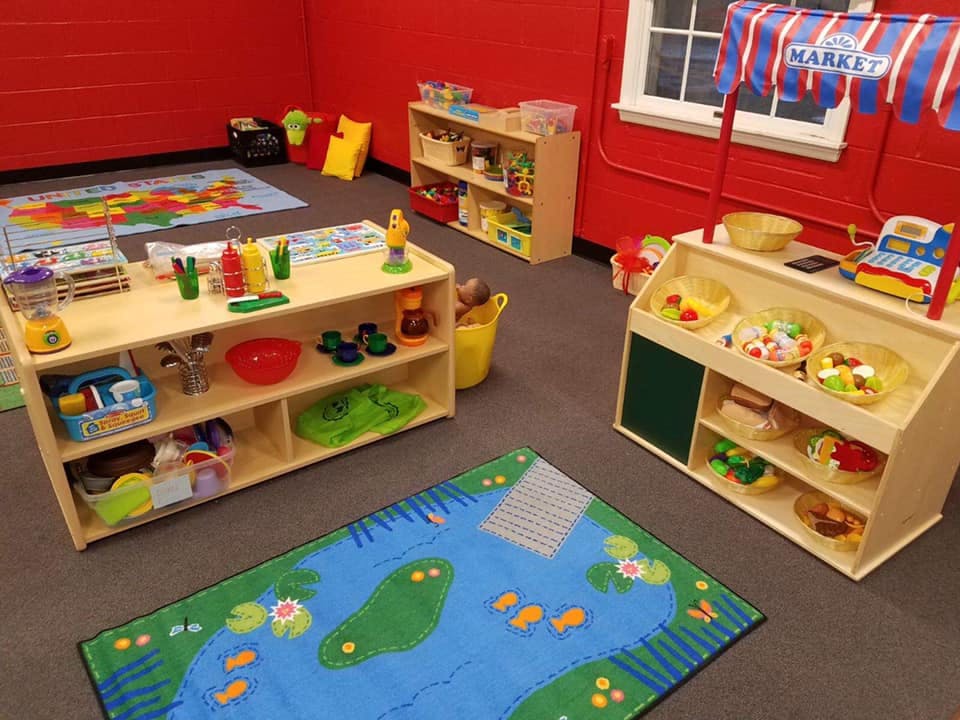 Playroom with toy kitchen, market stand, and colorful rugs