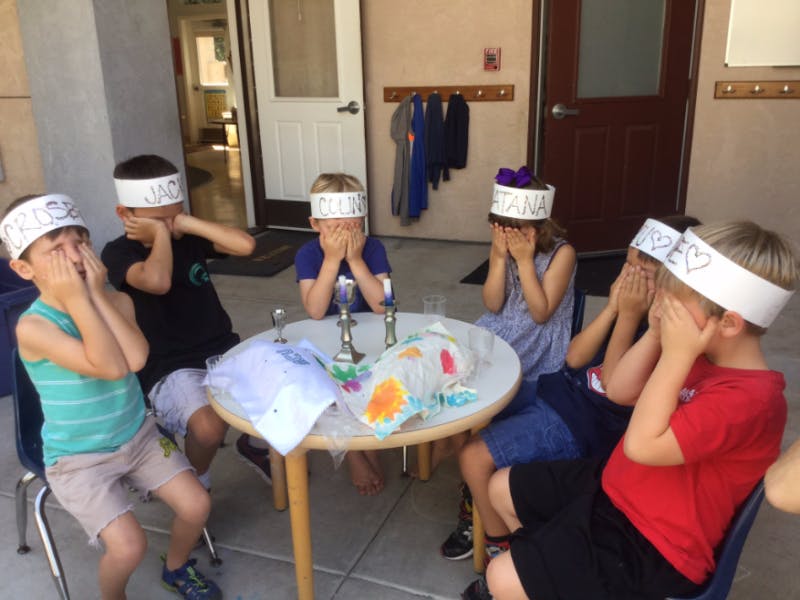 Children with headbands covering their eyes at a table