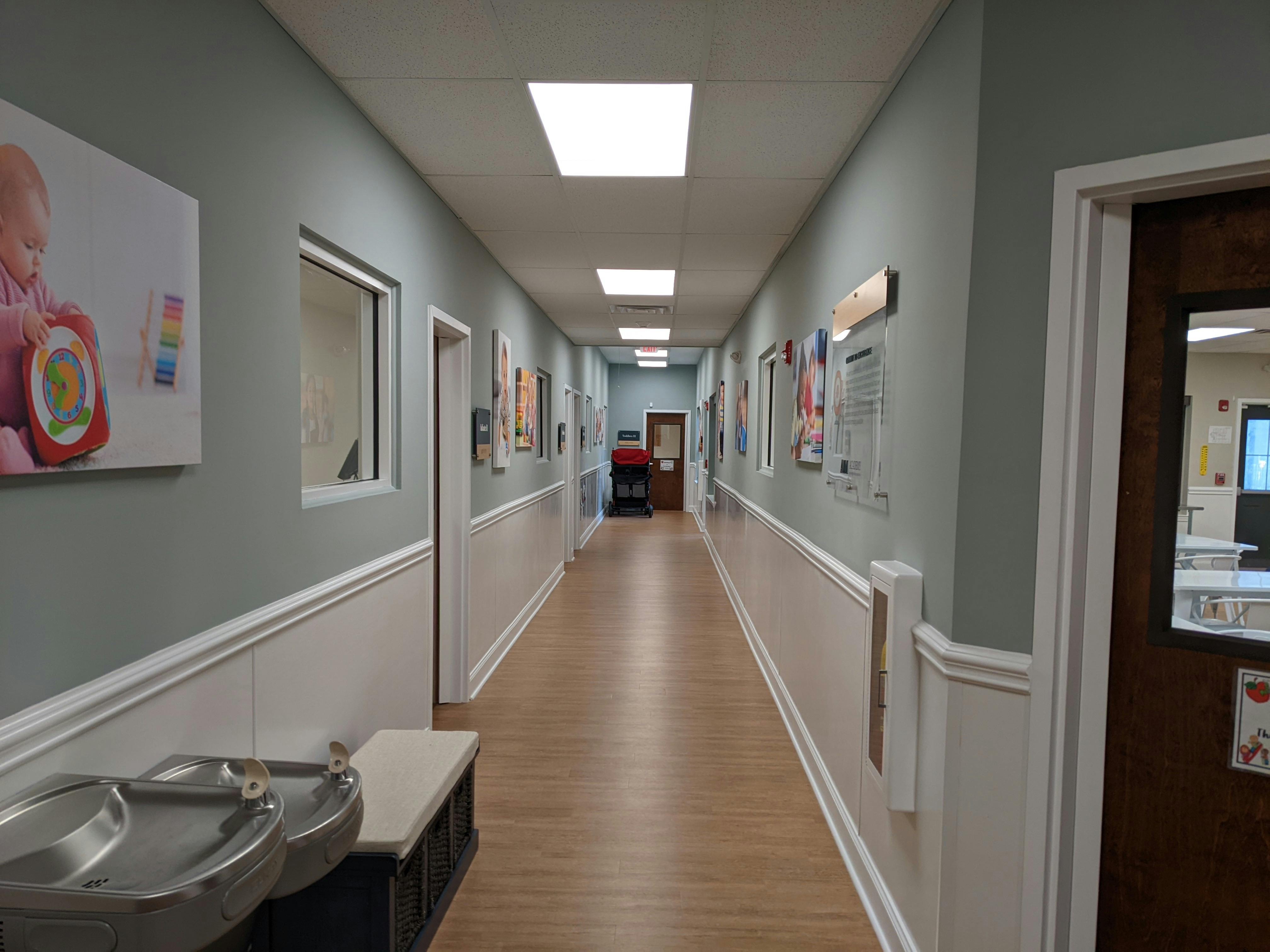 Long hallway with light blue walls, white wainscoting, and wood floor