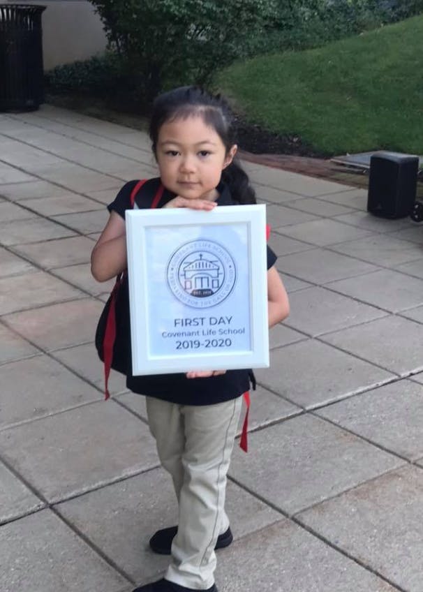 Child holding a framed sign that says "First Day 2019-2020"