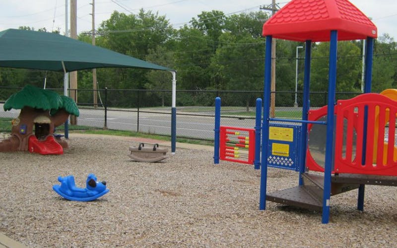 Empty playground with colorful equipment, including a tree-house slide and climbing structure