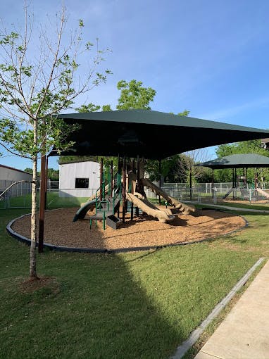 Playground with slides and climbing structures under a shade canopy