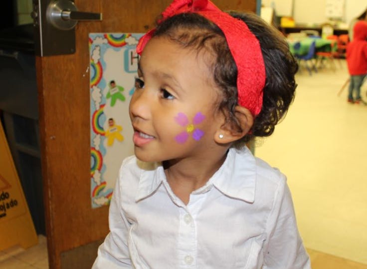 Child with a red headband and face paint on their cheek