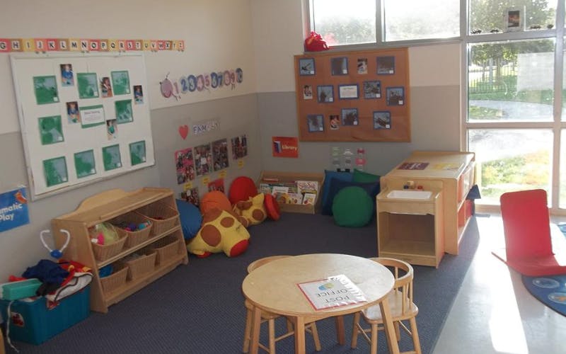Children's classroom with small table and chairs, toys, books, and wall displays