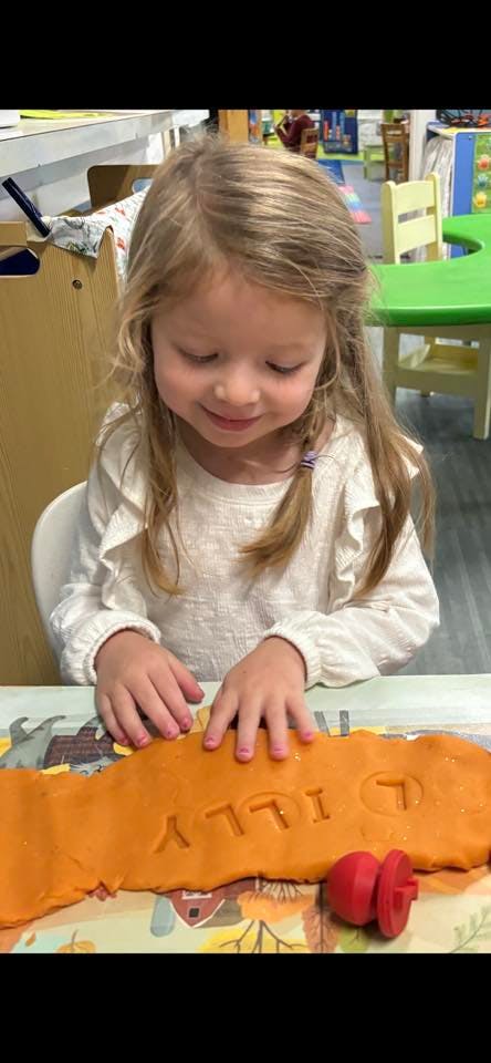 Child playing with clay with letters pressed into it