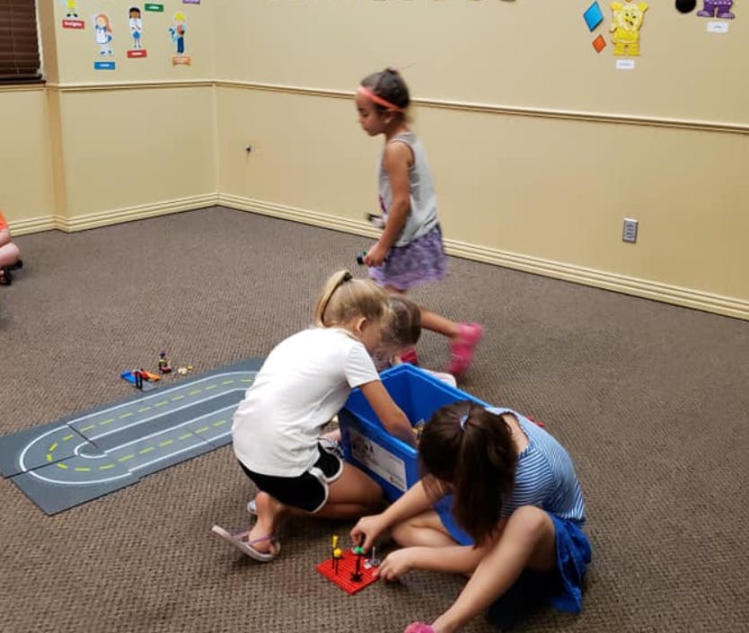 Three children playing with toys on a carpeted floor