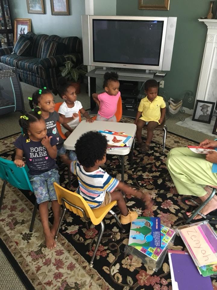 Children sitting around a small table with an adult