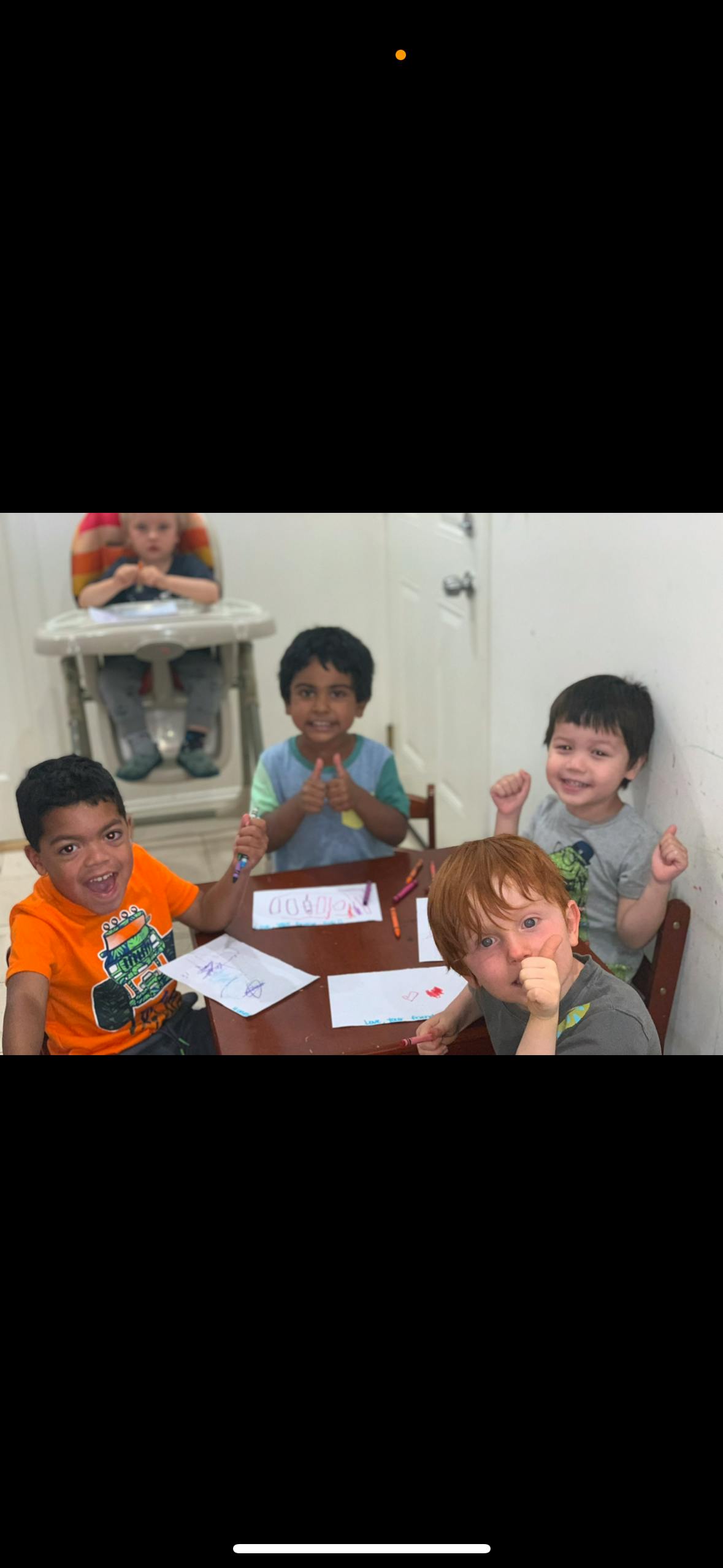 Four children sitting at a table with papers and crayons