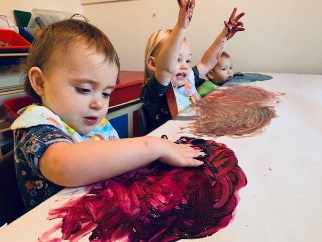 Children finger painting at a table