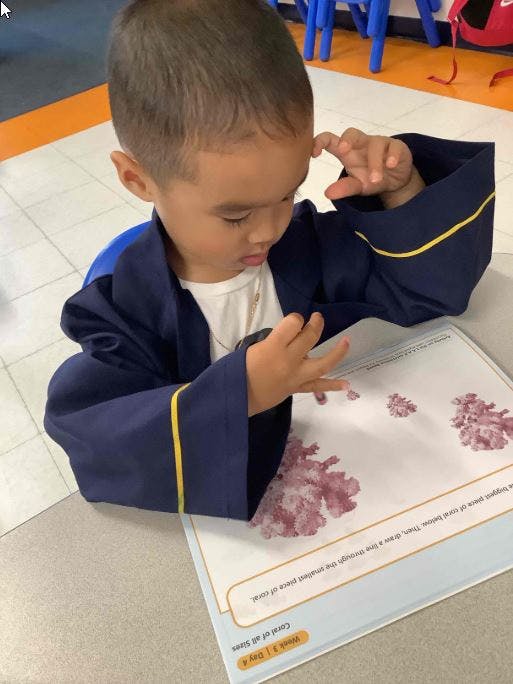 Child in a blue robe looking at a paper with pink blotches