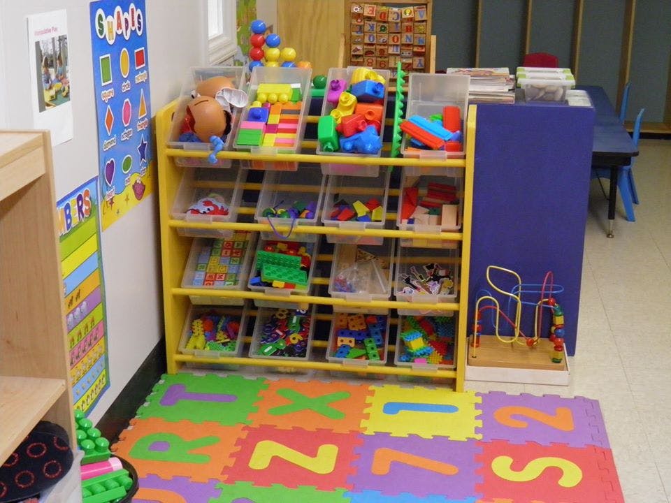 Toy shelf with colorful blocks and toys, alphabet mat on the floor