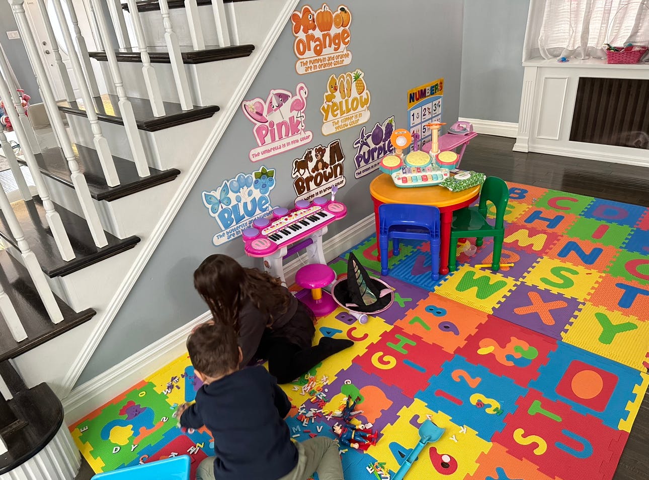 Two children playing on a colorful alphabet mat