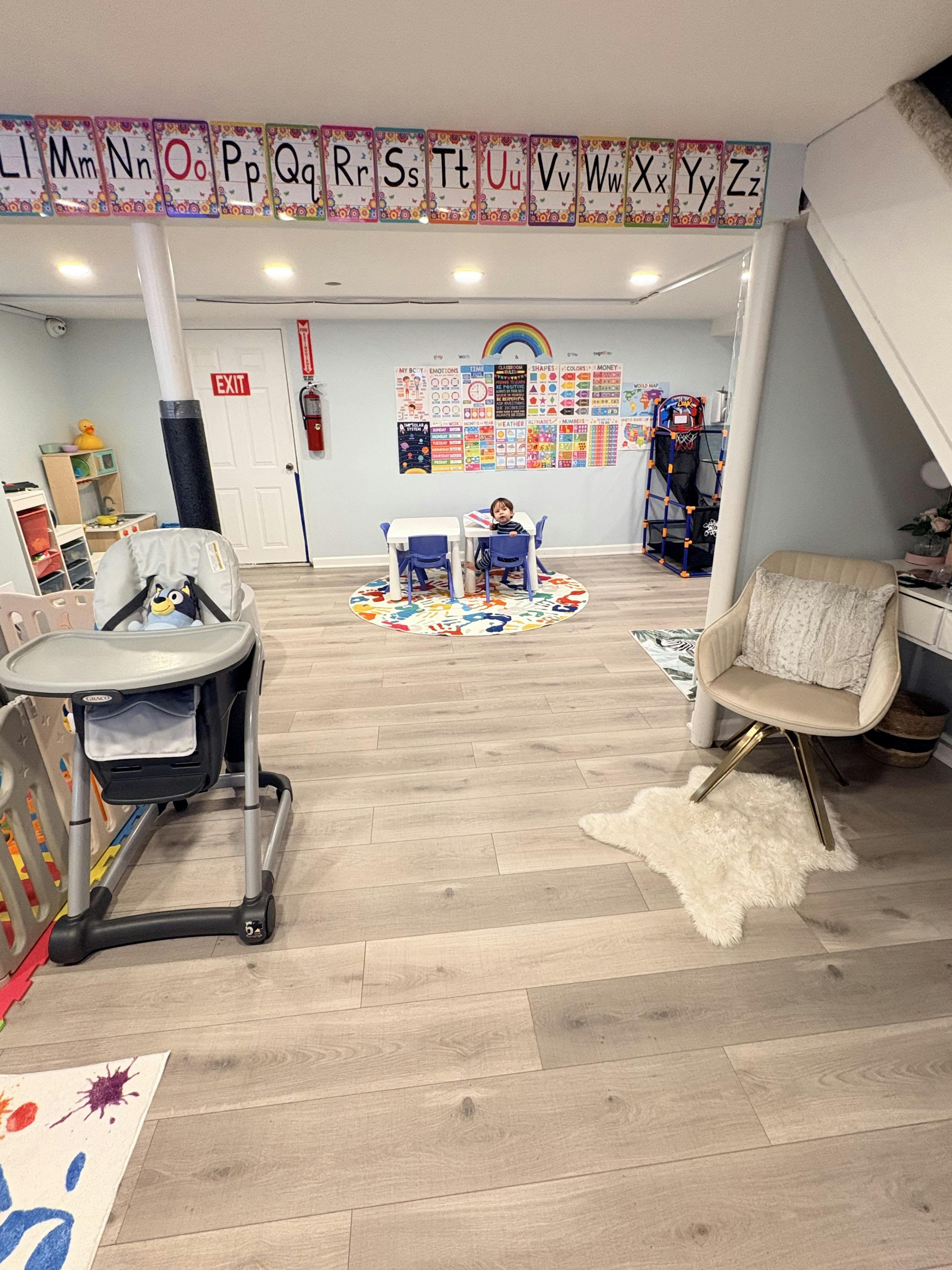 child seated at a small table in a bright playroom with educational posters