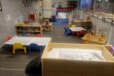 Classroom with small tables and chairs, shelves, and play areas