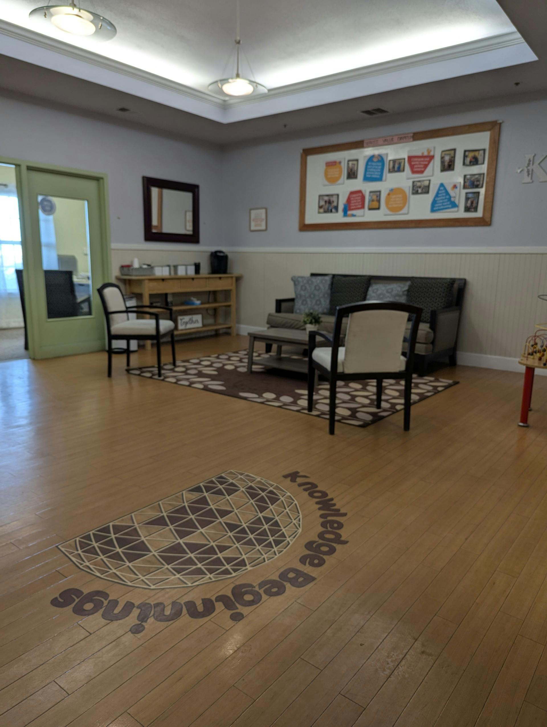 Lobby area with a sofa, chairs, coffee table, and a mural on the wall