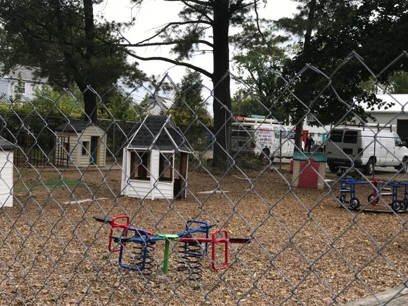 Playground with spring riders and playhouses behind a chain link fence