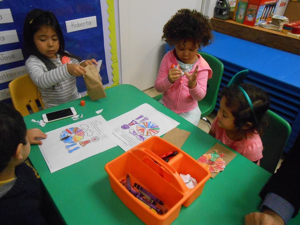 Children doing crafts at a table in a classroom