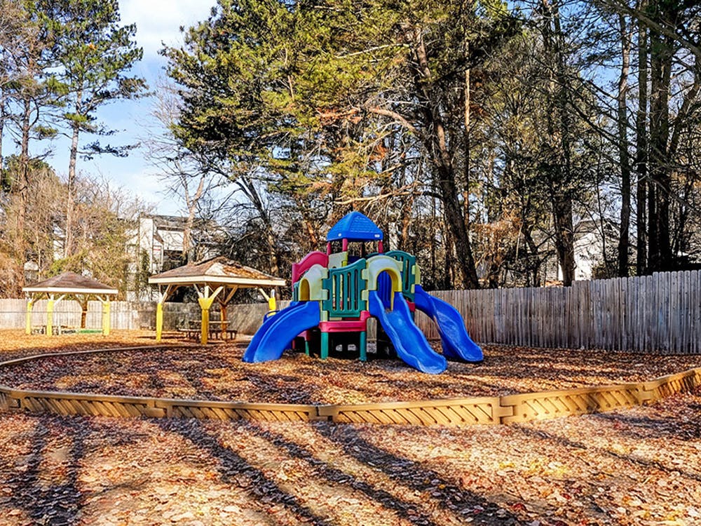 Colorful playground with slides, swings, and two gazebos under trees