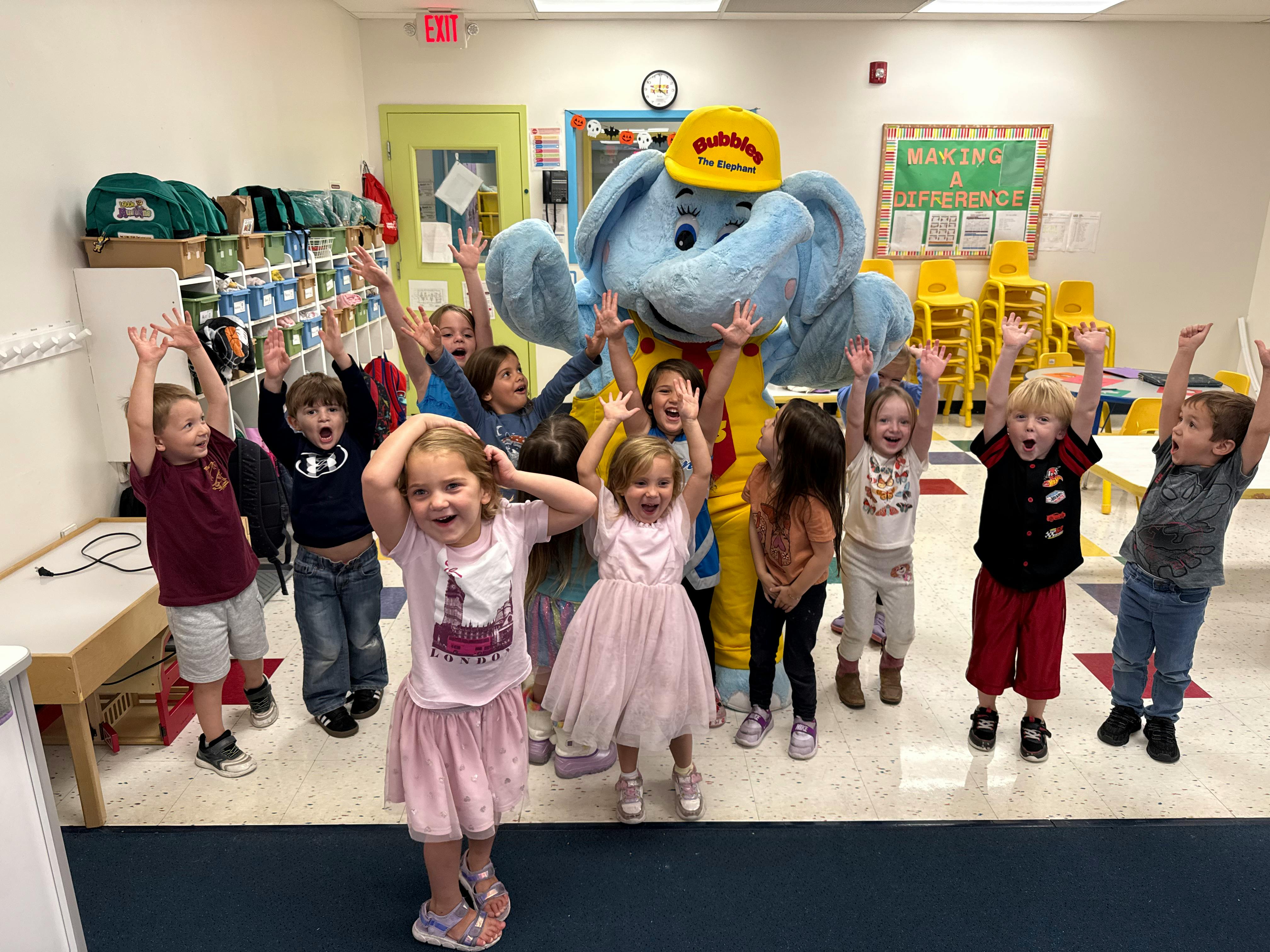 Children with arms raised around a person in an elephant costume