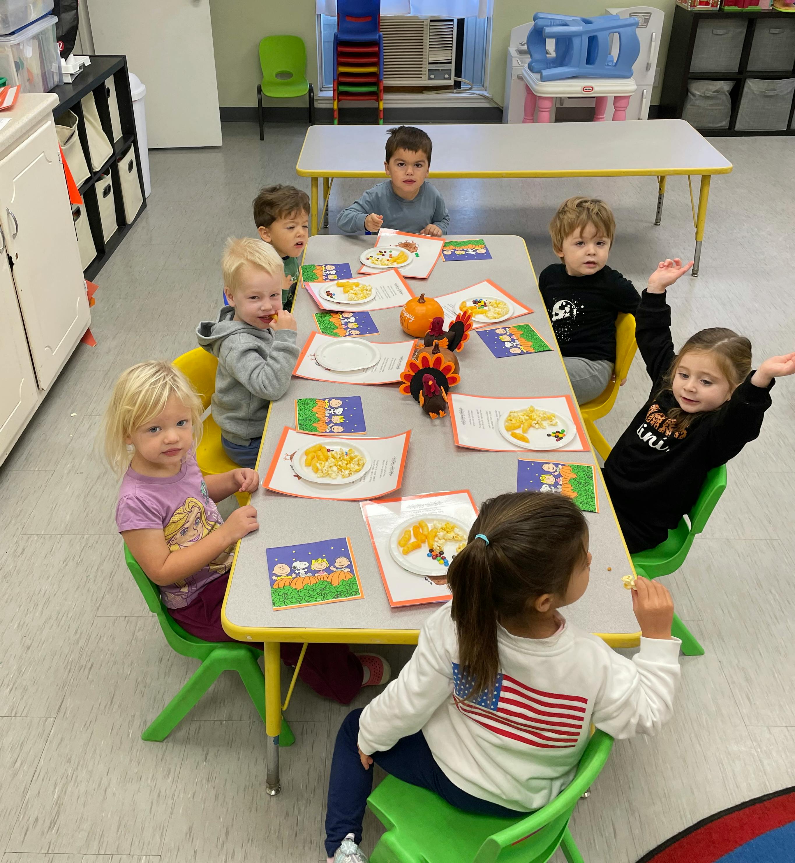 Group of children eating snacks at a table in a classroom