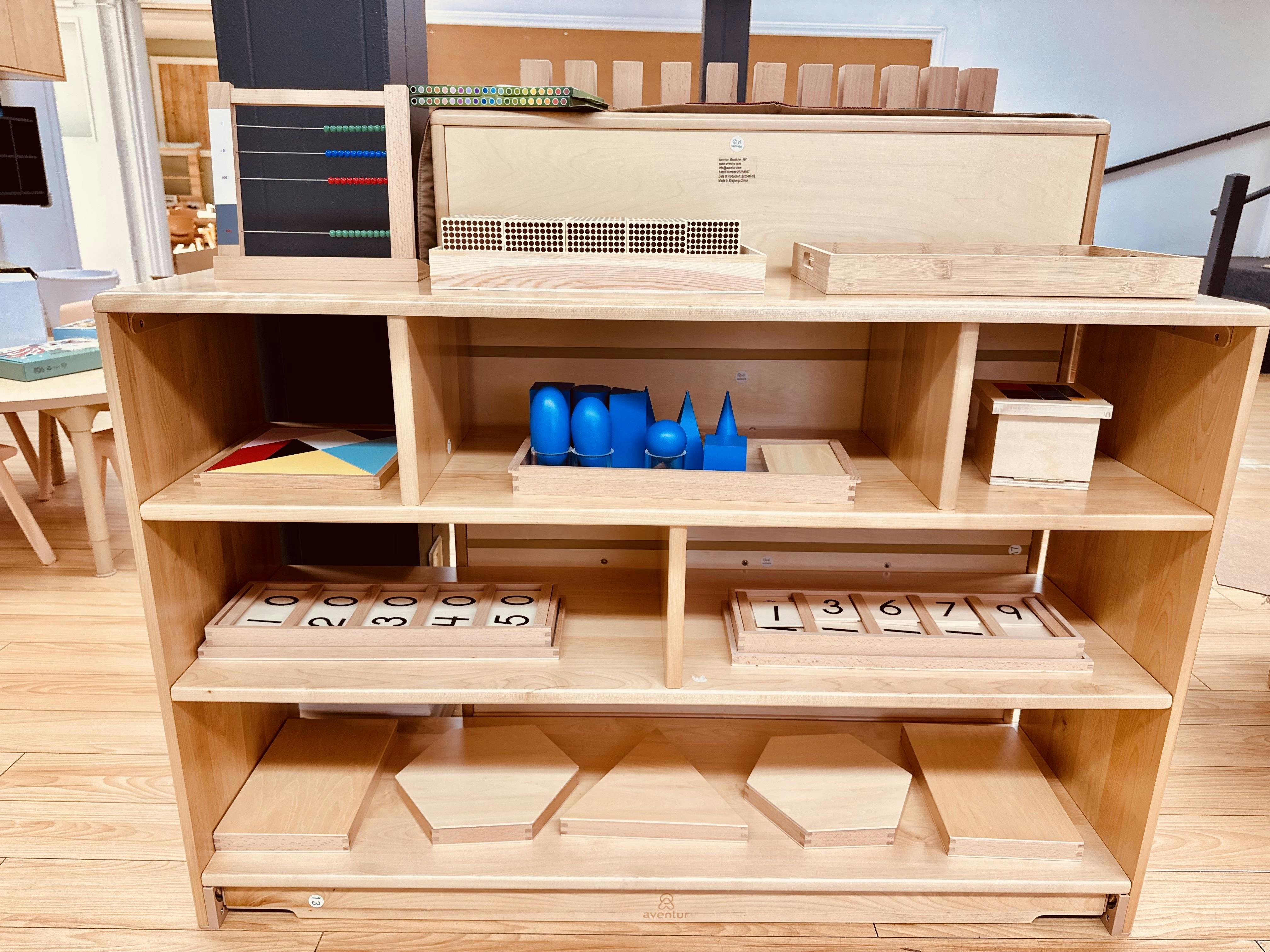 Wooden shelving unit displaying Montessori educational materials and math manipulatives