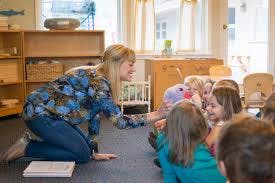 Adult kneeling and interacting with children in a classroom