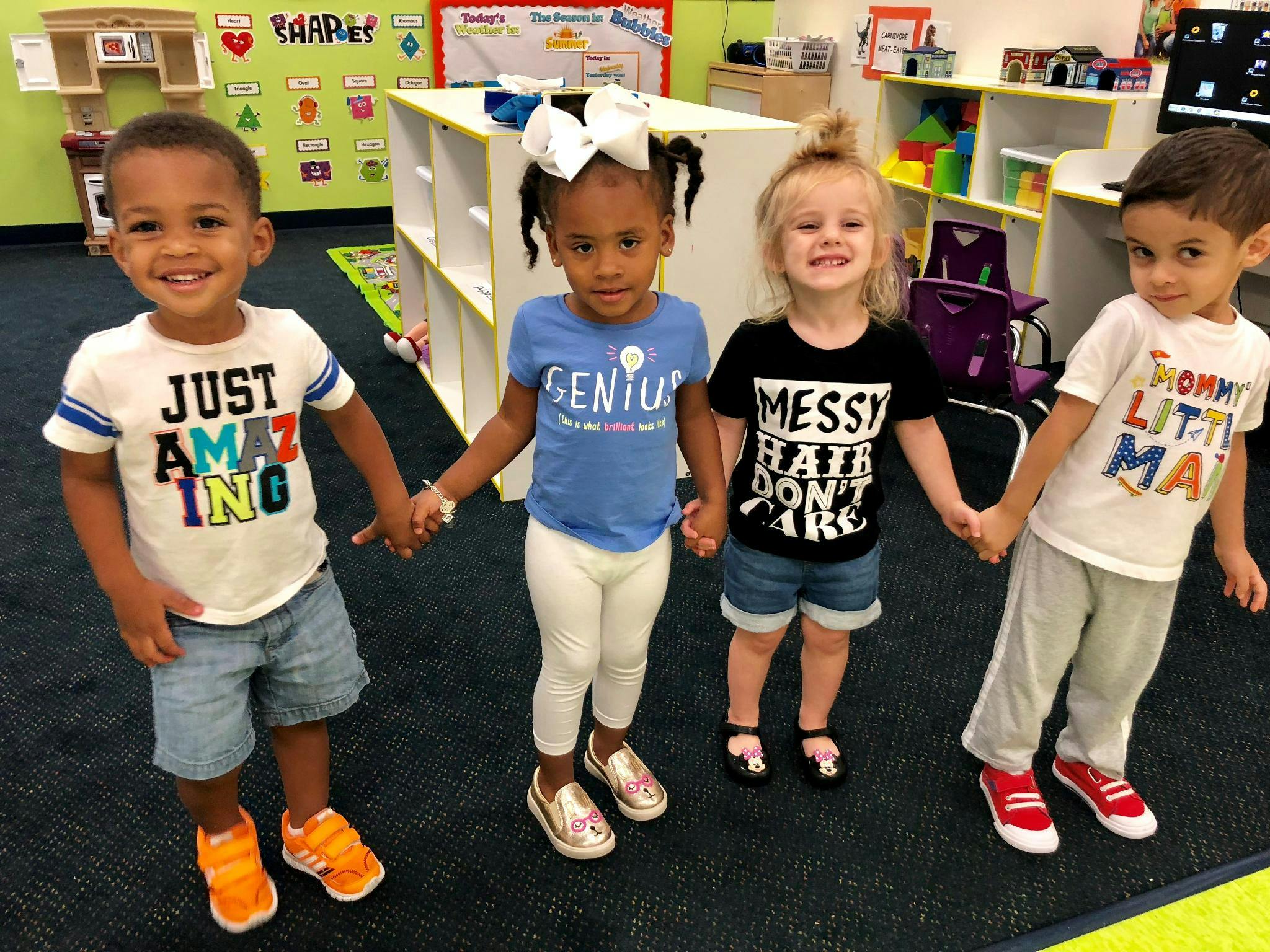 Four children holding hands in a classroom