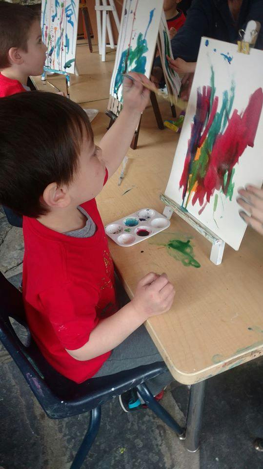 Child painting on an easel at a desk
