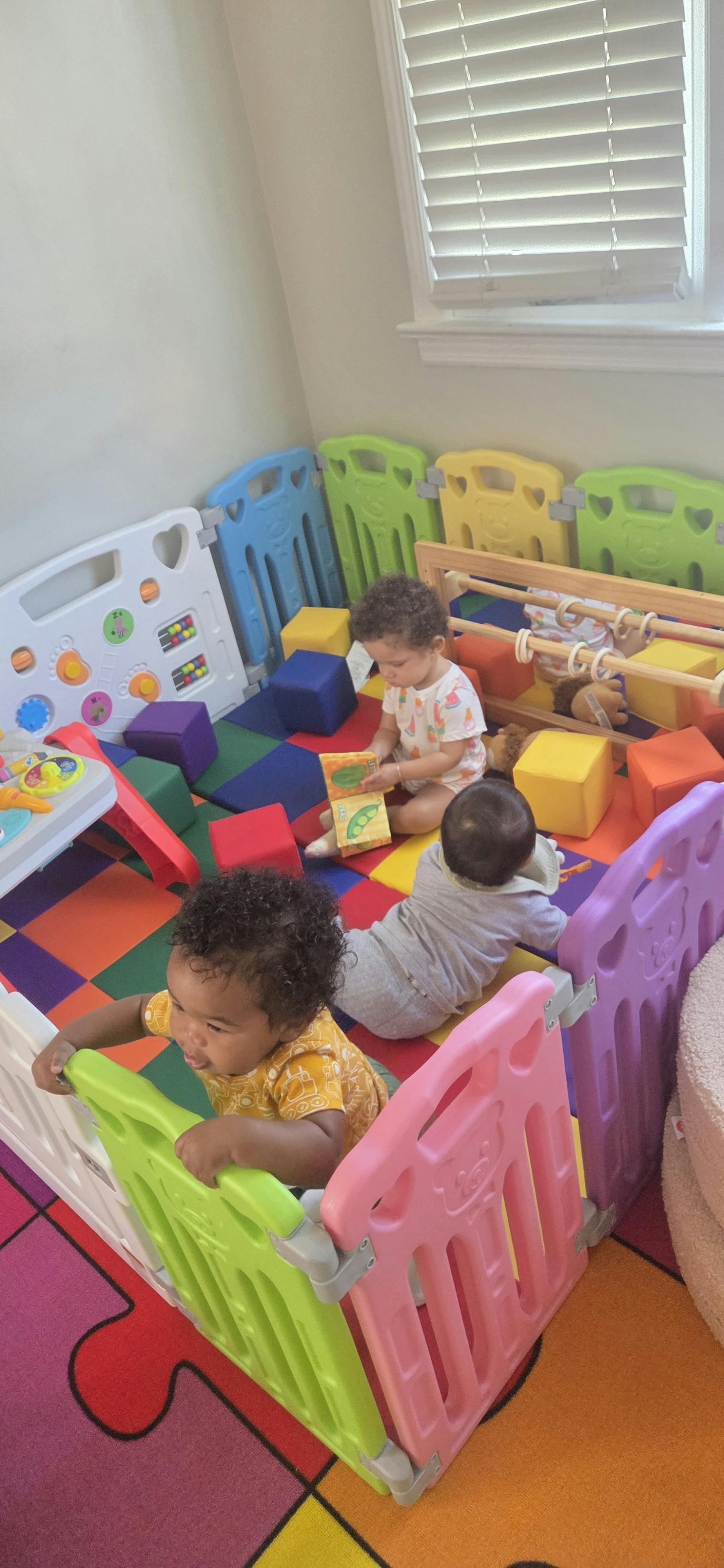 Three children playing inside a colorful plastic playpen