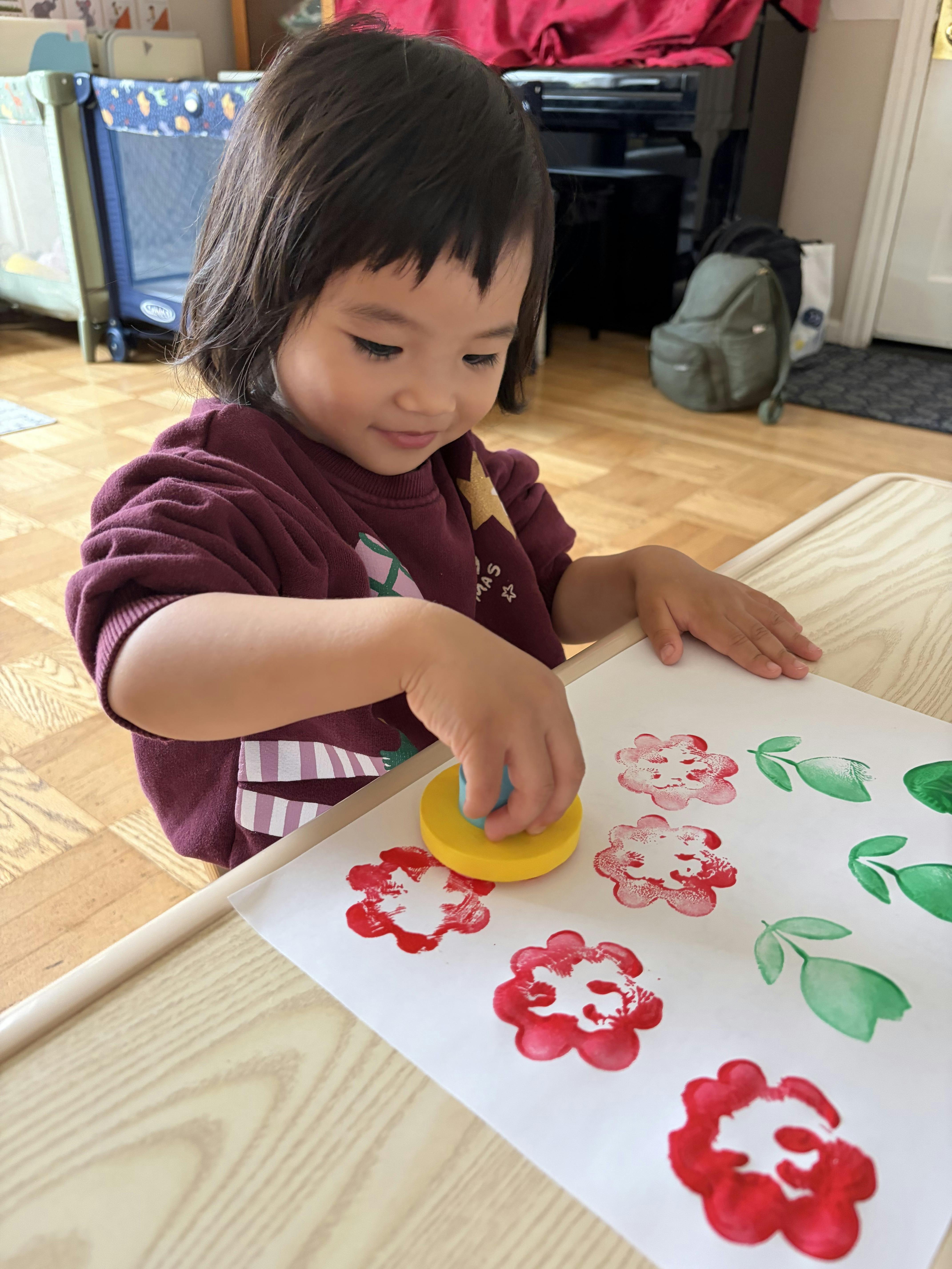 Child using a stamp to print flower shapes on paper