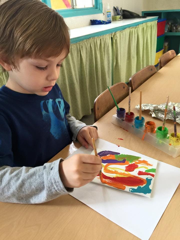 Child painting on a canvas with a paintbrush
