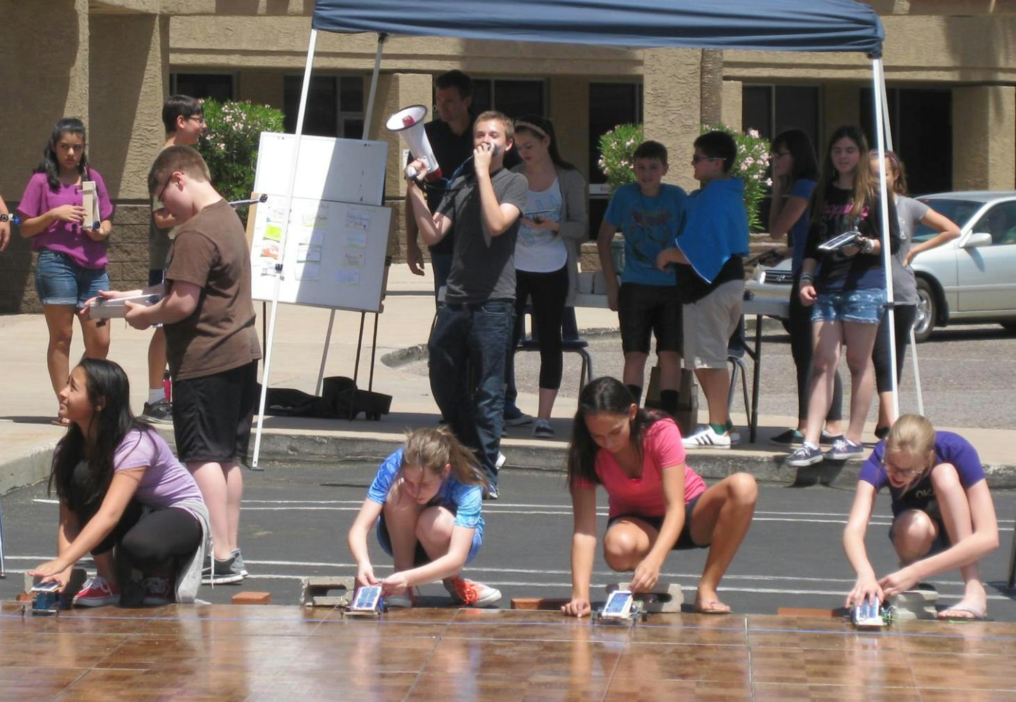 Teens and children participating in an outdoor activity with small cars
