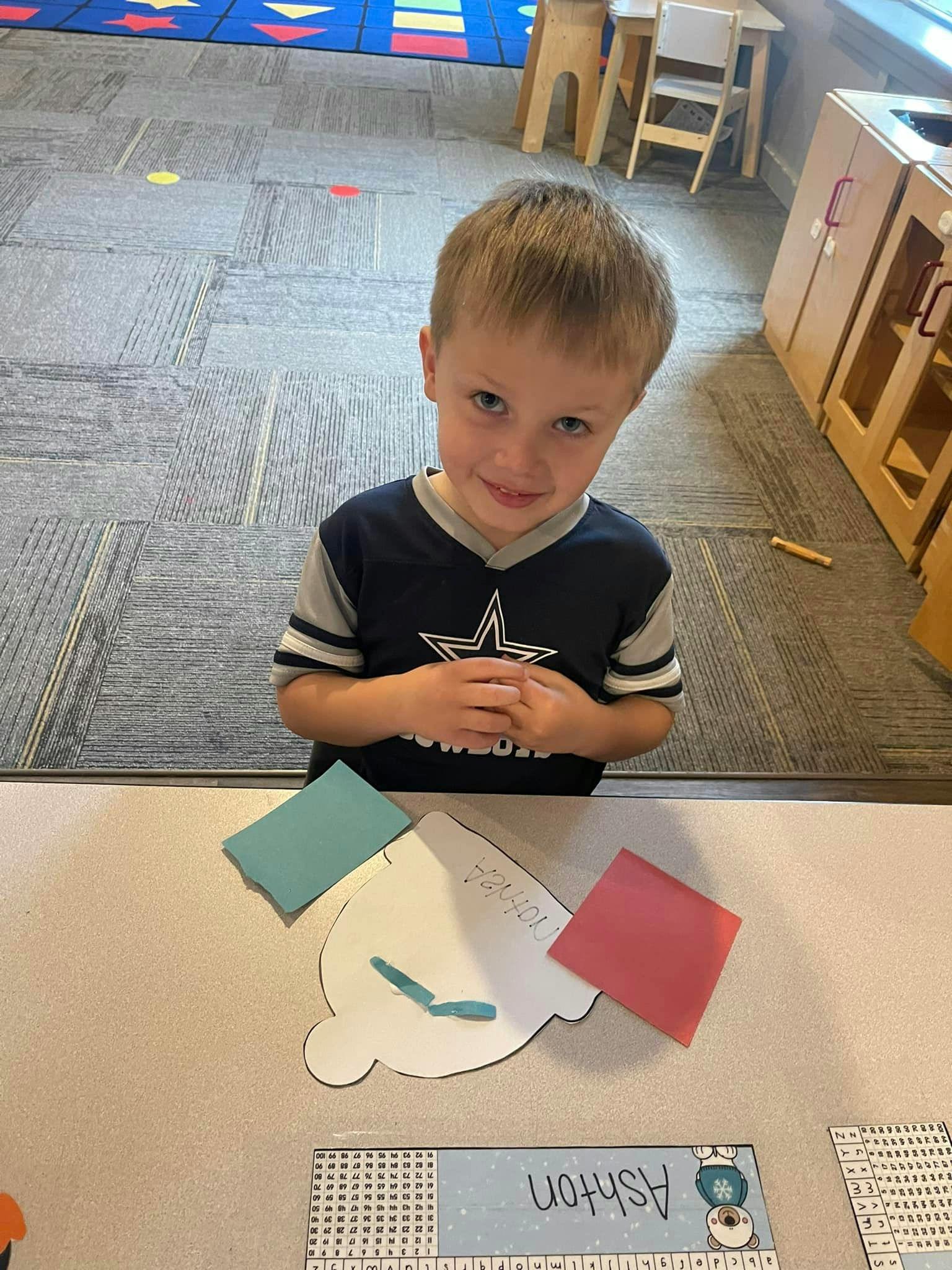 Child standing at a table with craft supplies