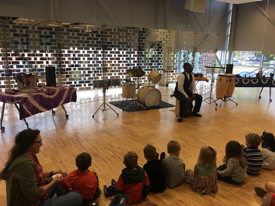 Person playing drums for children sitting on the floor