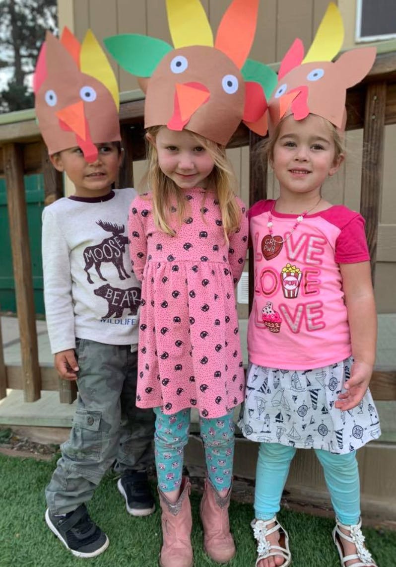 Three children wearing turkey hats