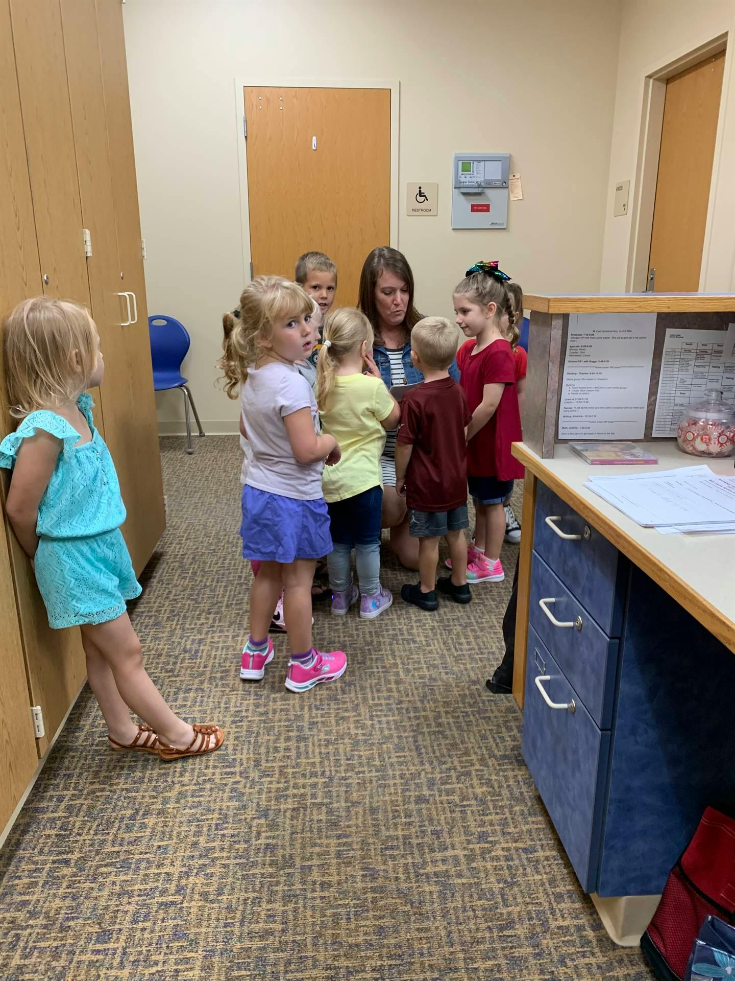 Adult person with several children gathered around a desk