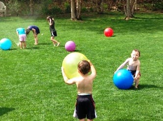 Children playing with large balls on a grassy lawn