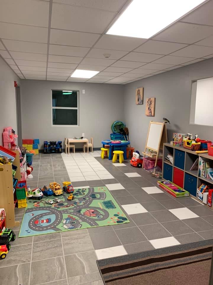 Playroom with toys, small tables, and a road map rug