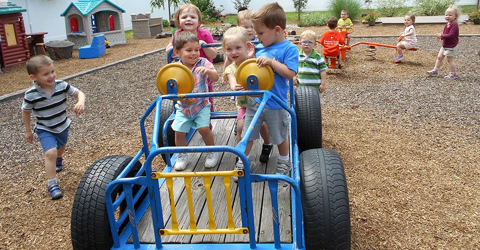 Children playing on a playground, some in a tire car