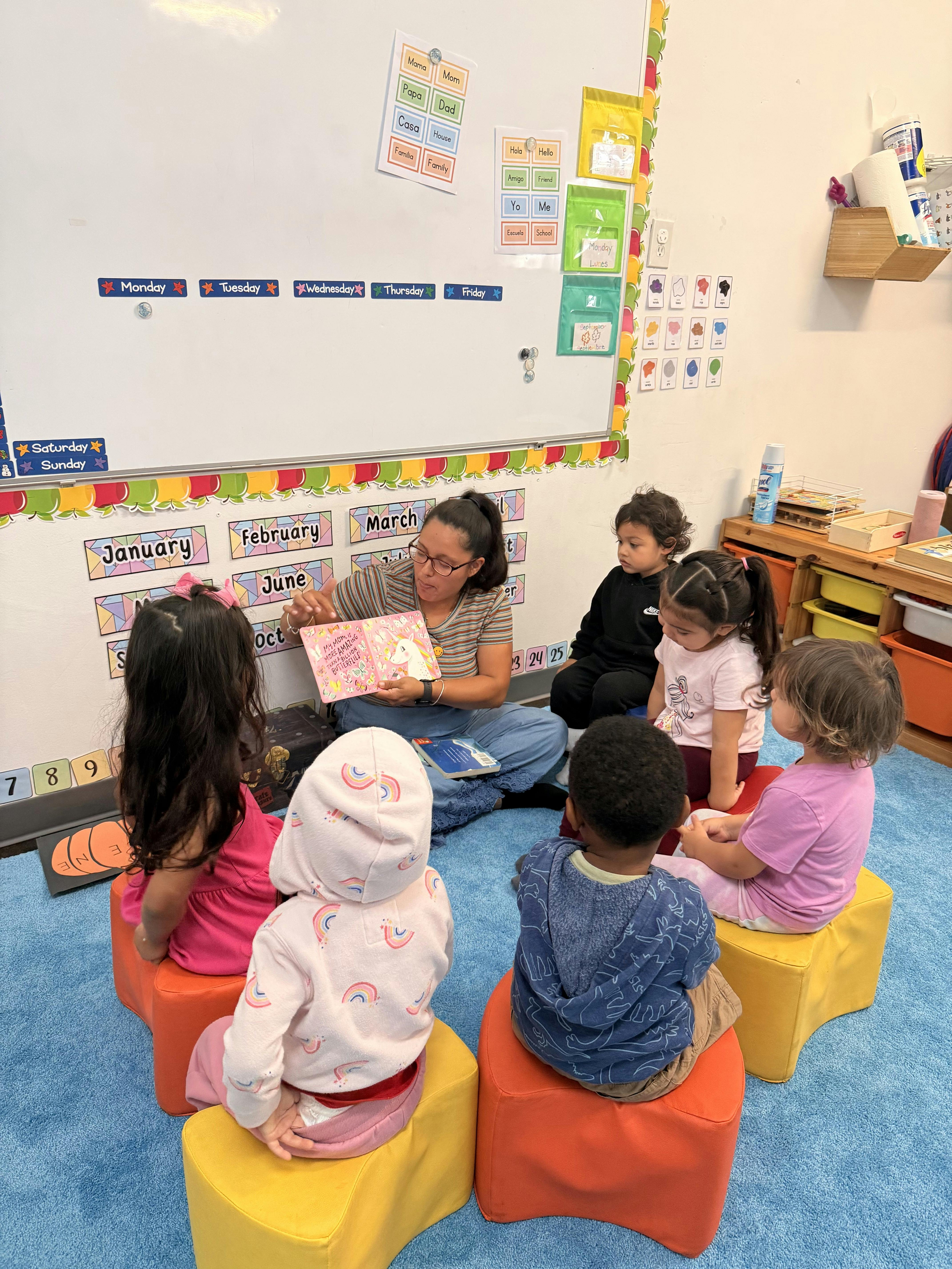 Person reading a book to a group of children in a classroom