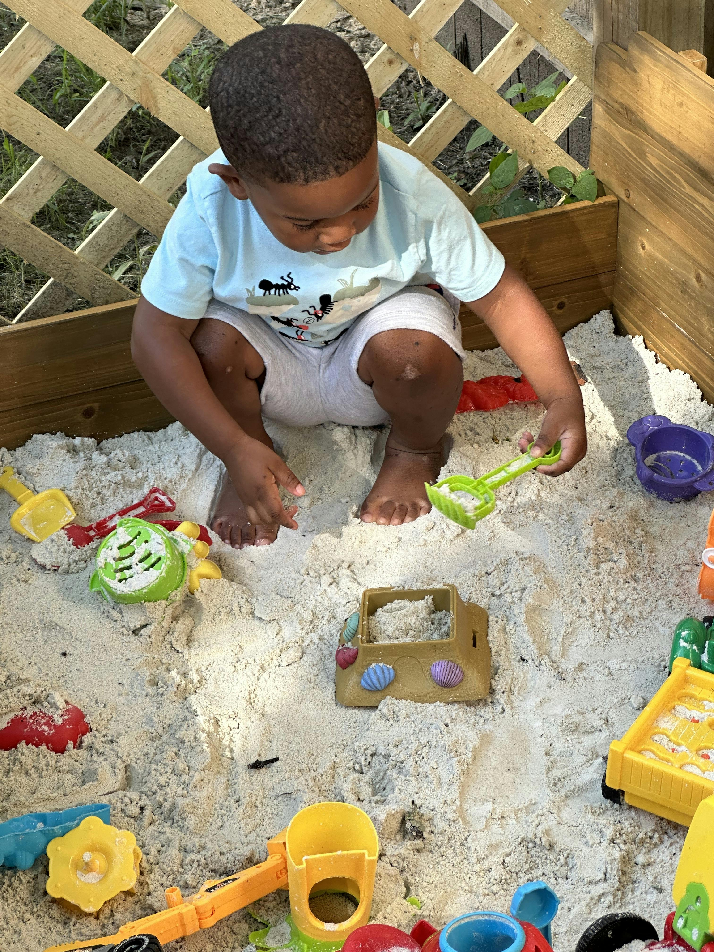 Child playing in a sandbox with toys