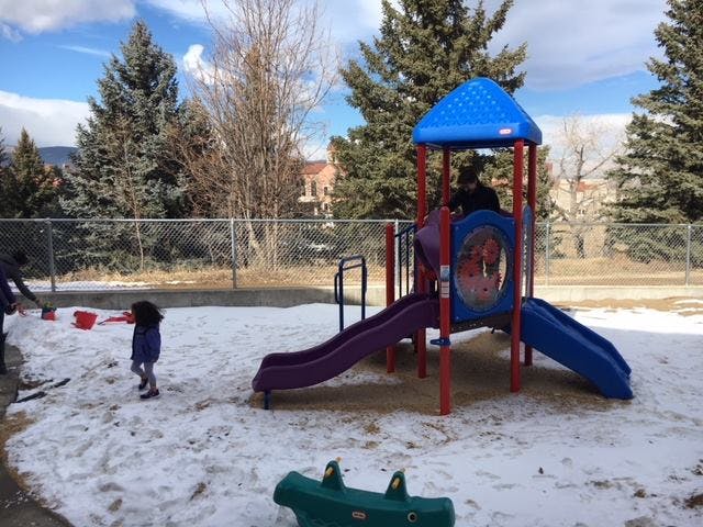 Child playing in snow next to a playground structure