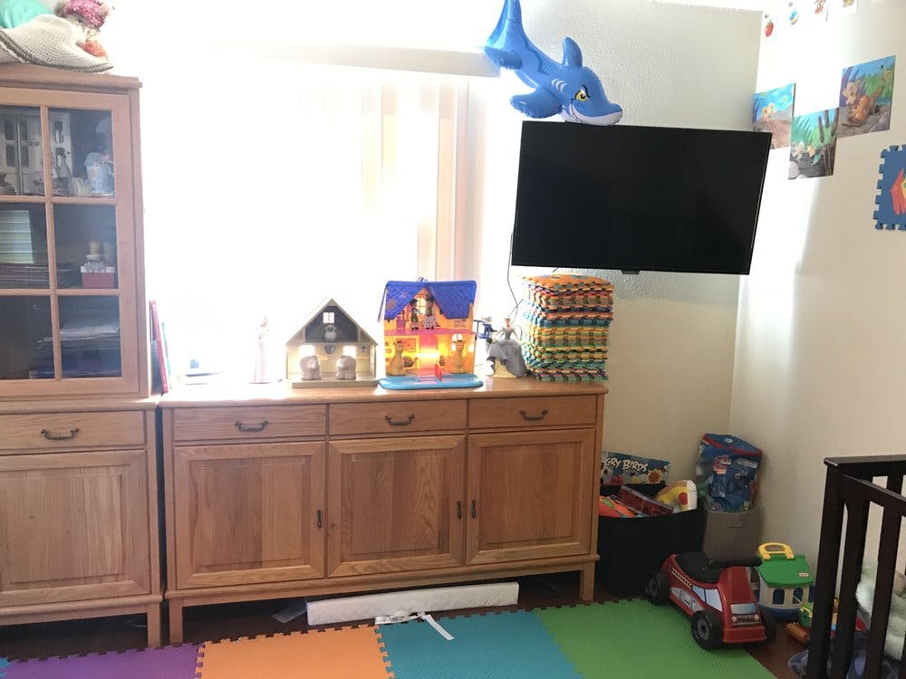 Wooden cabinets with a television mounted above and toys on the floor