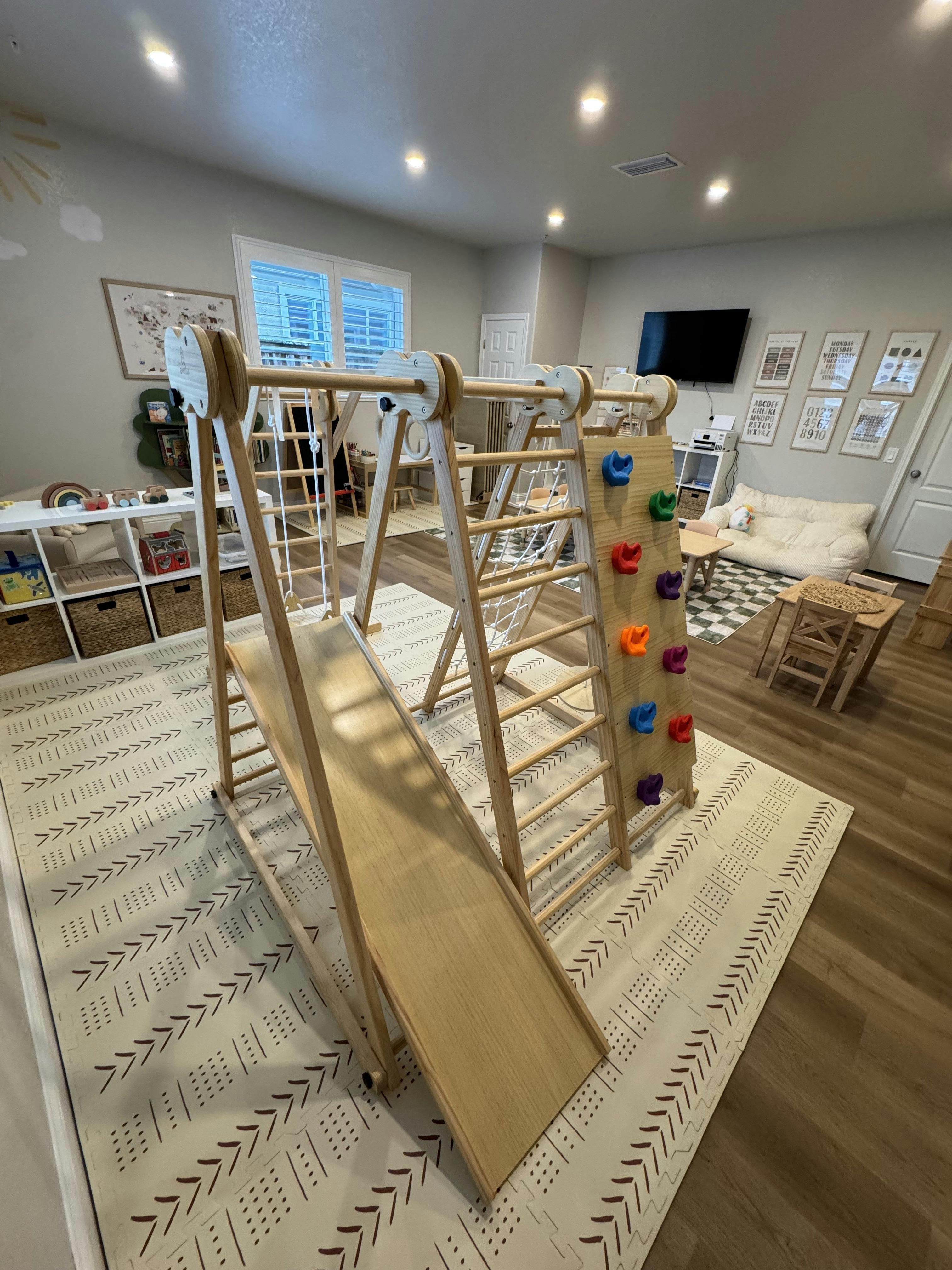 Indoor wooden play structure with a slide and climbing wall