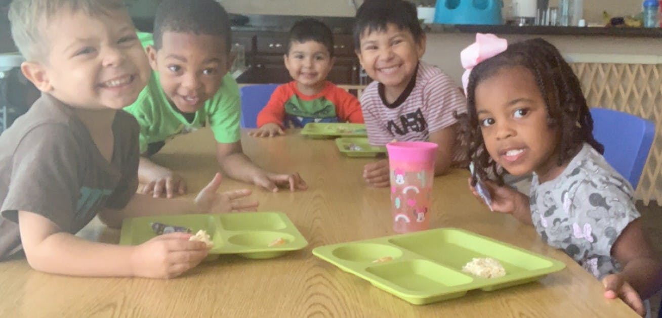 Five children sitting at a table with plates